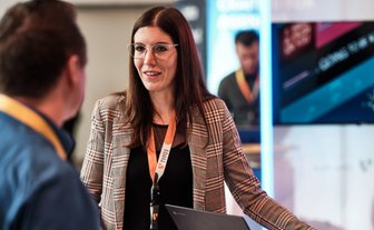 Geschäftliche Gesprächssituation zwischen einer Frau und einem Mann, im Hintergrund ein Screen