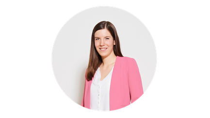 Eine Frau mit langen, braunen Haaren lächelt freundlich in einem rosa Blazer vor einem weißen Hintergrund.