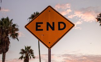 A traffic end sign before the backdrop of a sundown