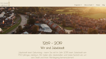 Eine Luftaufnahme von Jubelstadt zeigt eine ruhige Wohngegend mit modernen Häusern und sanften Hügeln im Hintergrund.