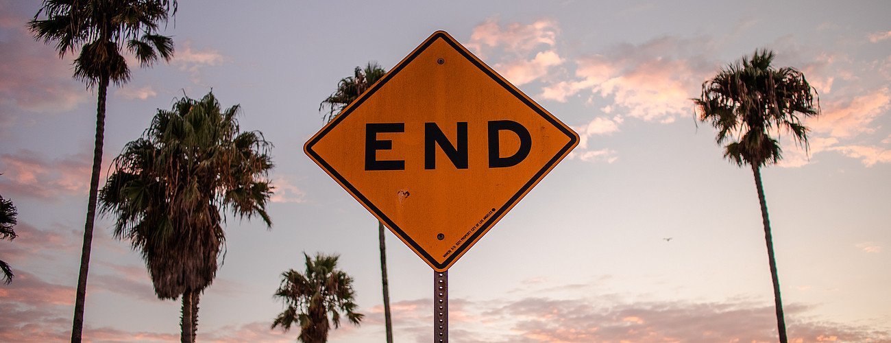 A traffic end sign before the backdrop of a sundown