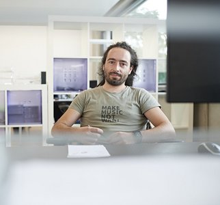 Webdesign-Mitarbeiter am Schreibtisch sitzend und in die Kamera schauend